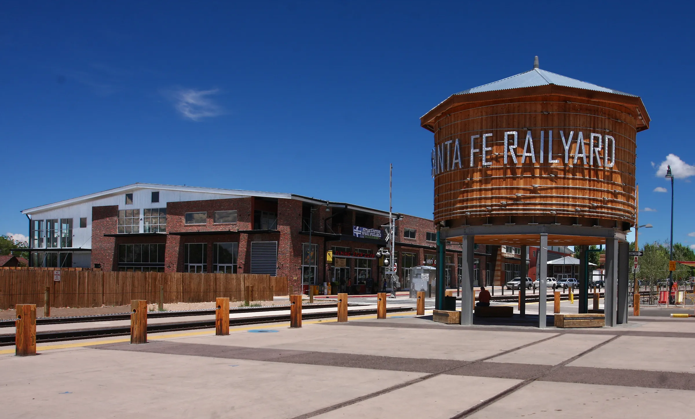 The wooden Santa Fe Railyard water tower against a deep blue sky, the brick depot buildings beyond