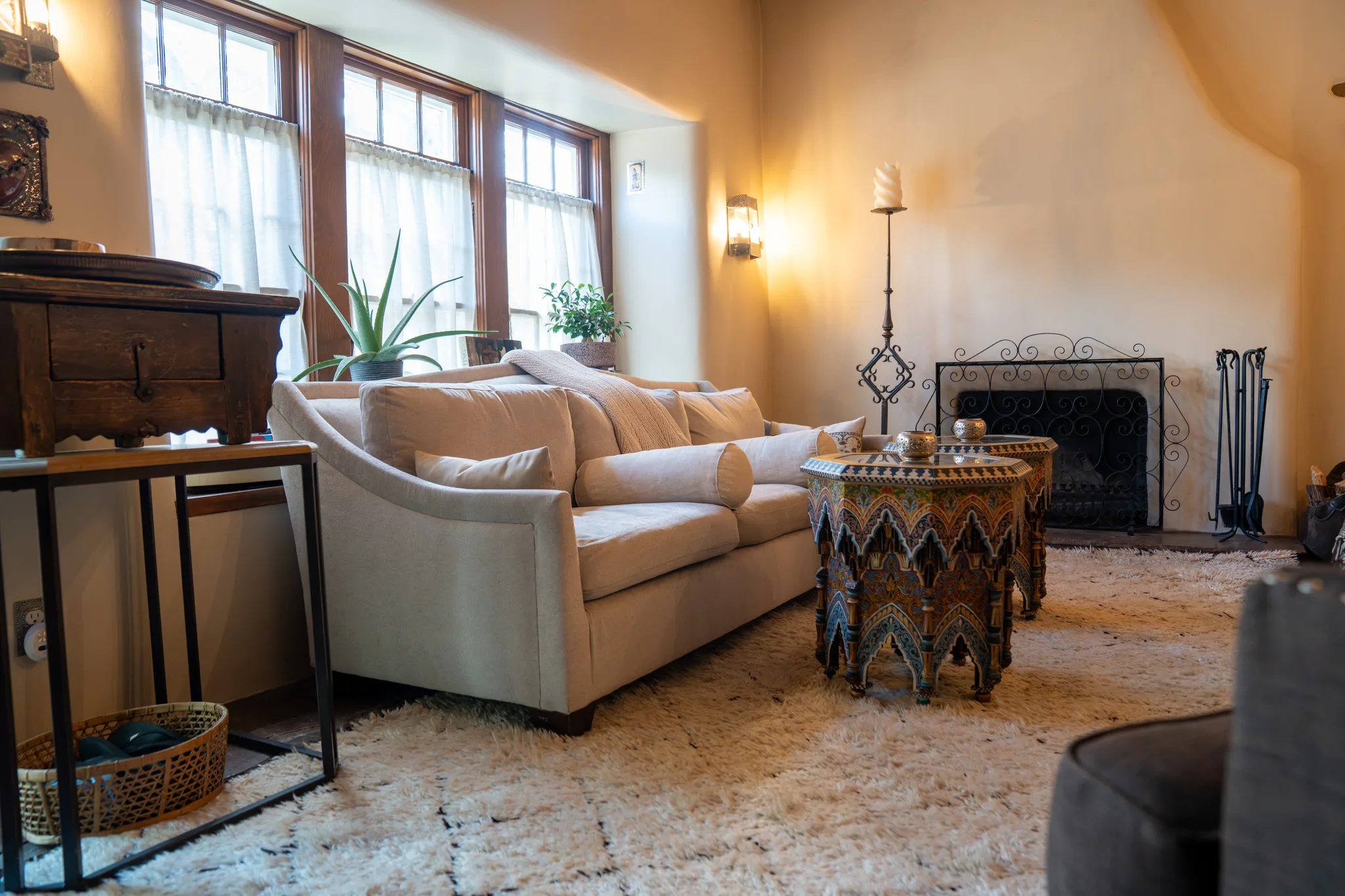 The Los Santos sala in daylight: a cream sofa and inlaid Moroccan tables before the fireplace, tall paned windows behind