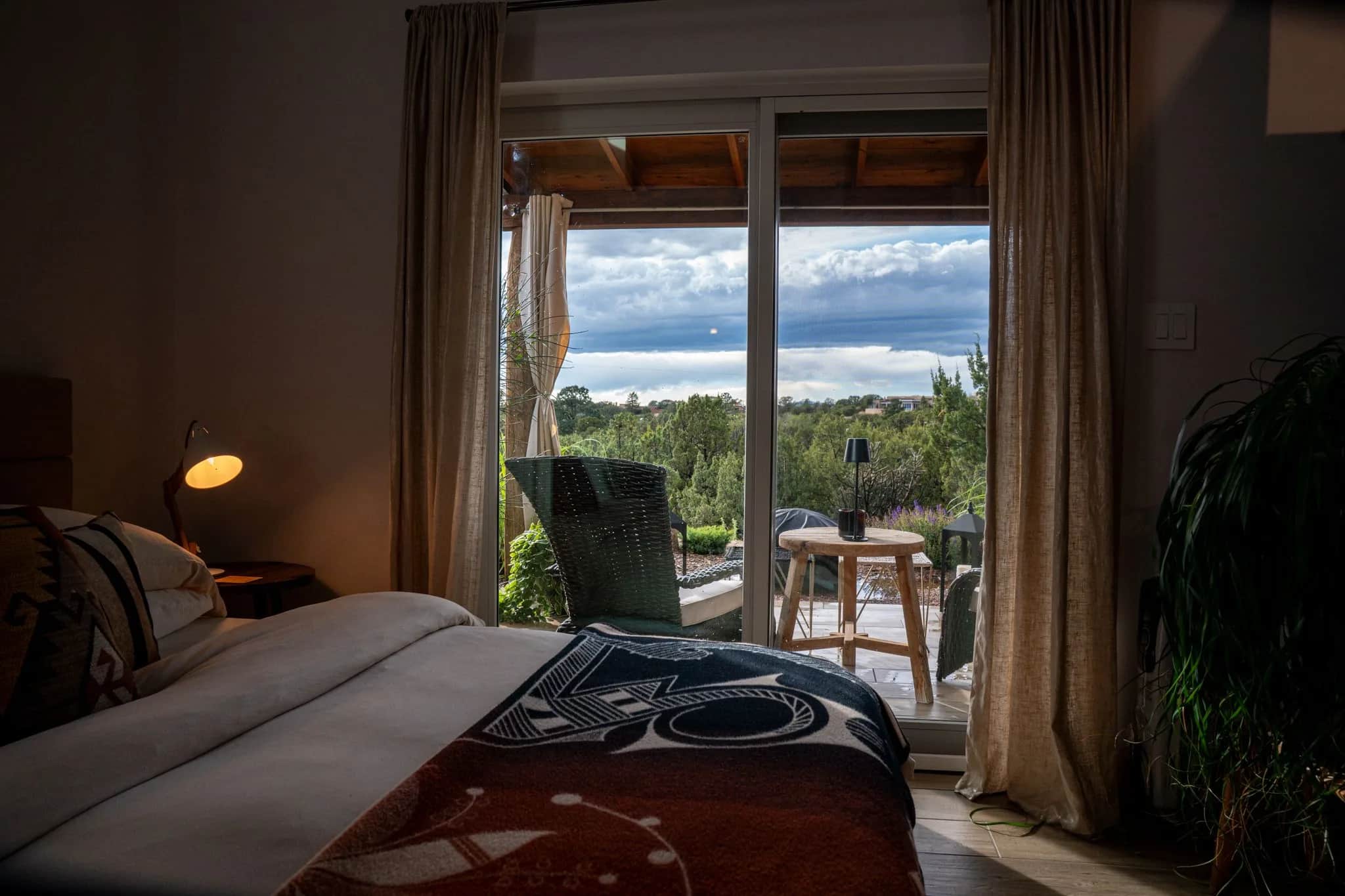 The Farmhouse 1 bed facing a wall of glass doors open to the west, piñon and sky beyond