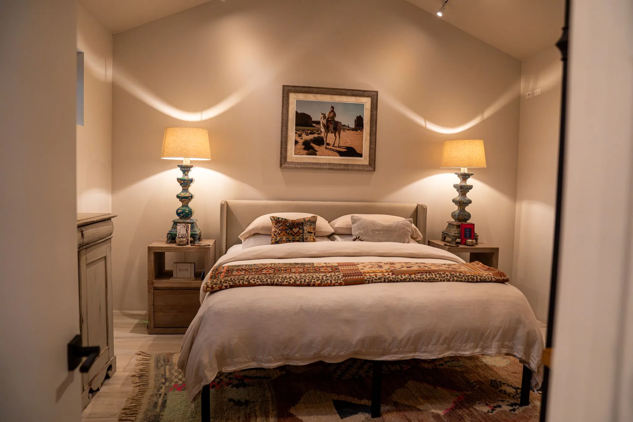 A king bed between two turned lamps under a desert painting in the Farmhouse 2 bedroom