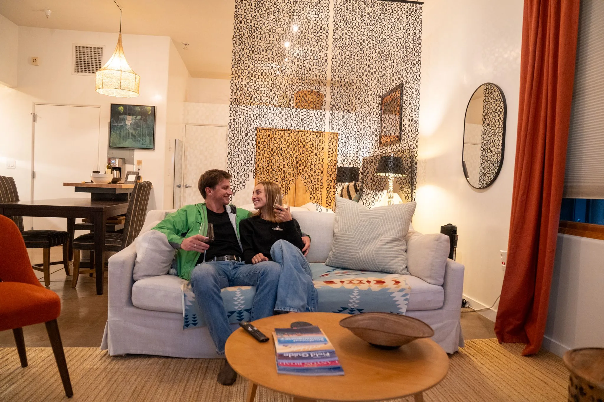 A couple laughing together on the white sofa, the beaded screen and the bed behind them