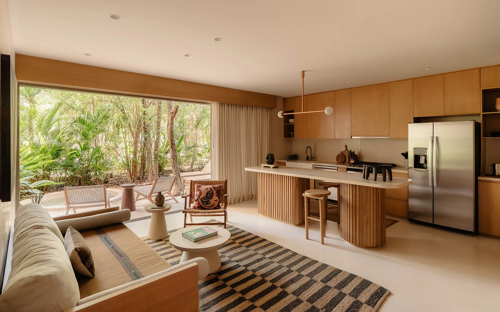 An open living room and kitchen in warm wood and plaster, with floor-to-ceiling glass open to the garden