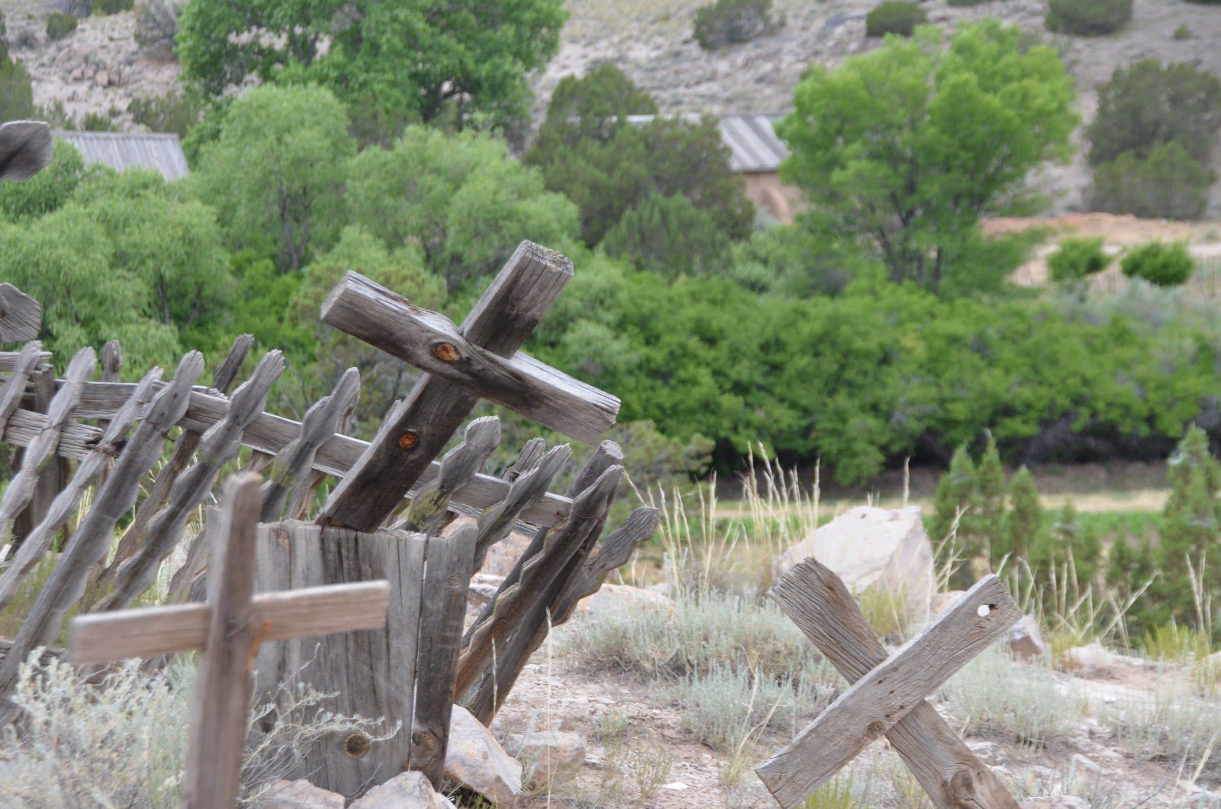 Weathered wooden crosses in the old cemetery at El Rancho de las Golondrinas, cottonwoods beyond